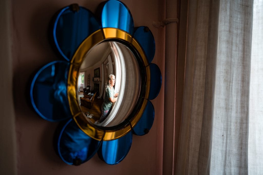 Woman reflected in a decorative circular mirror.