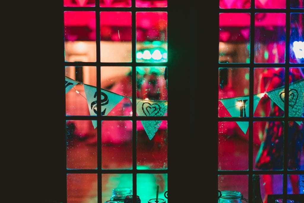 Colourful window with festive bunting at night.