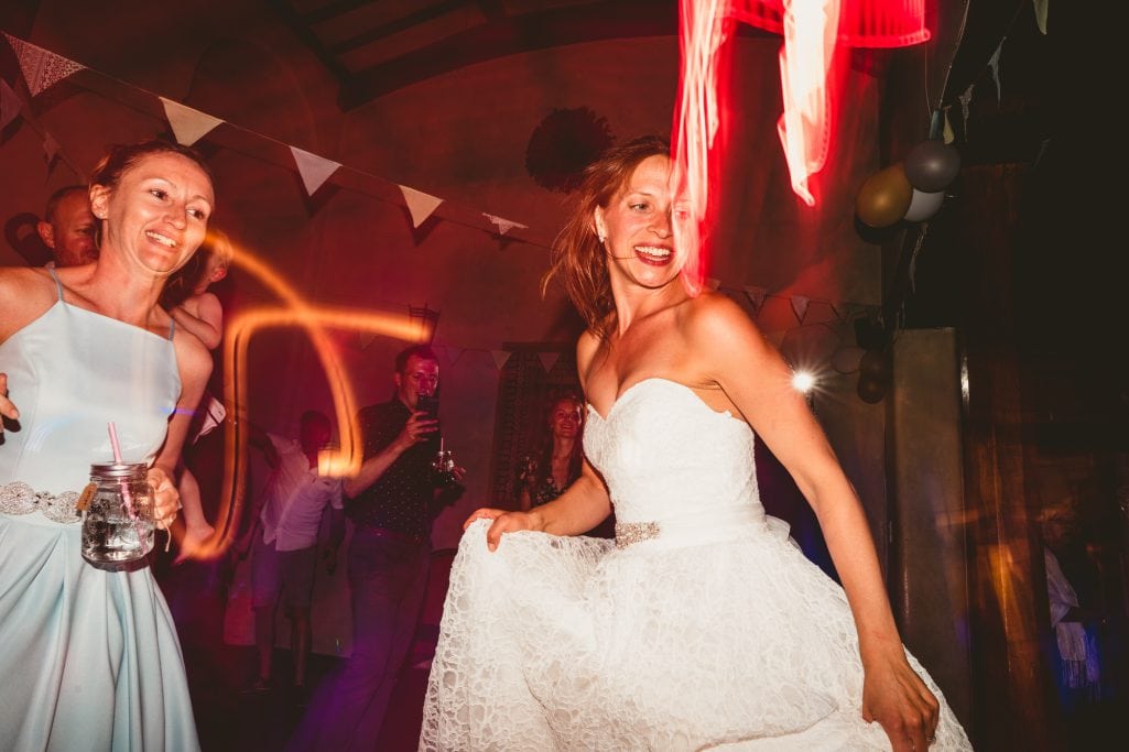 Bride dancing joyfully at wedding reception with guests.