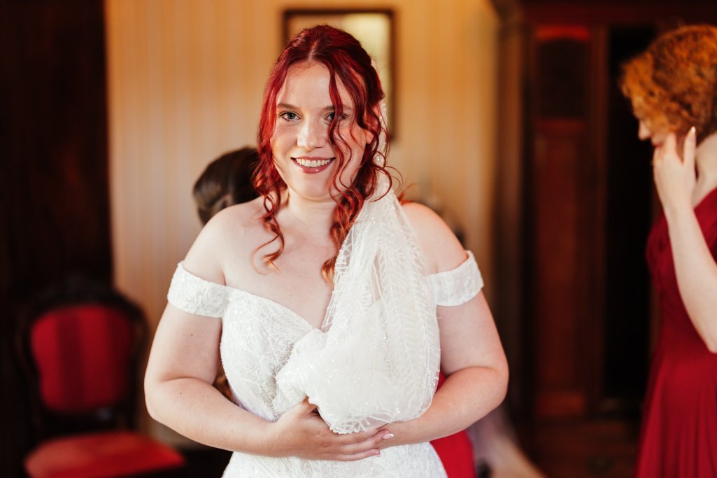 Bride with red hair smiling in wedding dress.