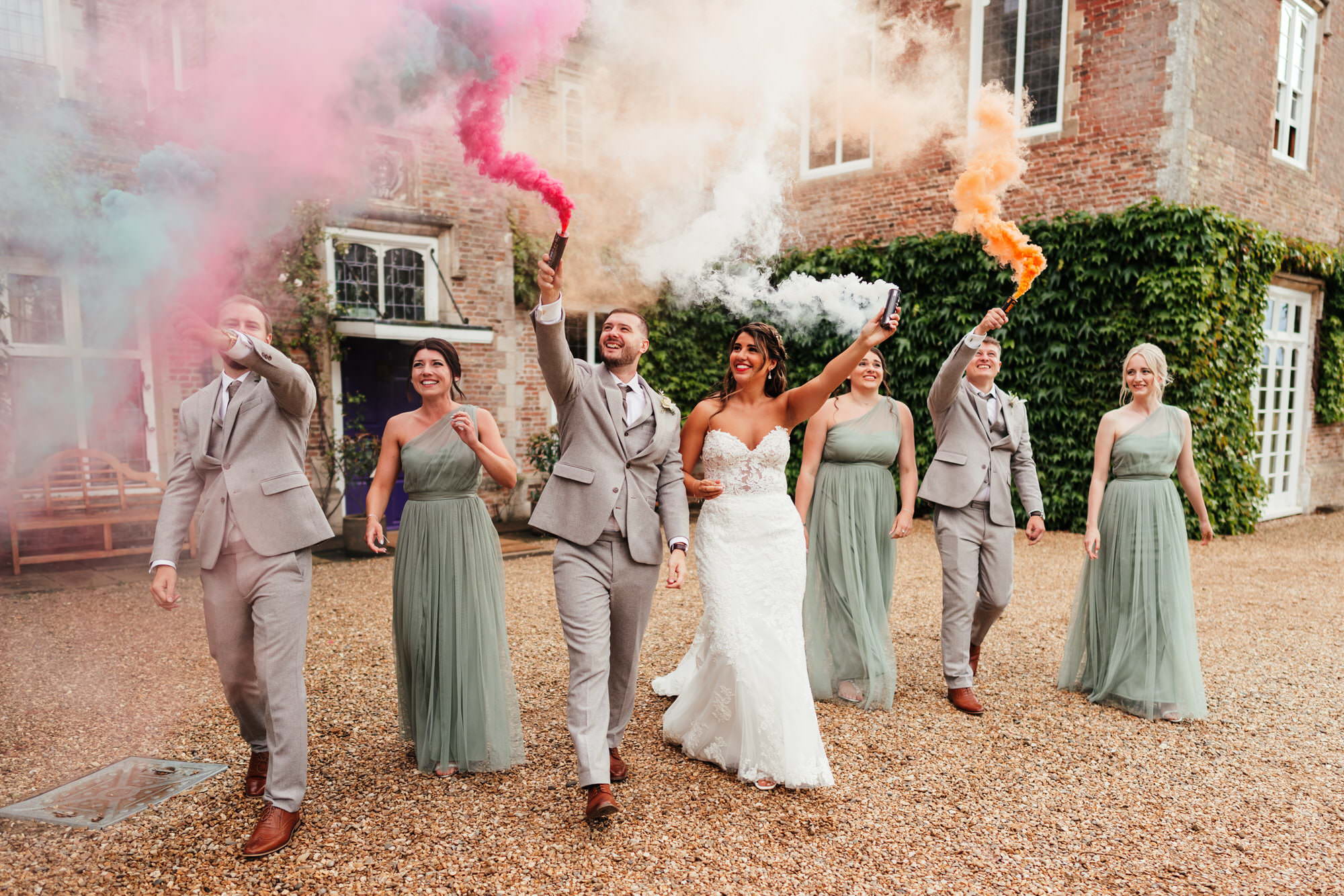 Wedding party with colourful smoke flares outdoors.