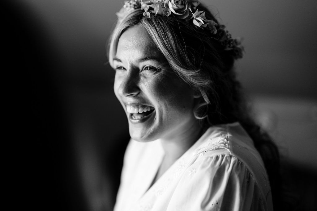 Joyful bride with floral headband in monochrome.