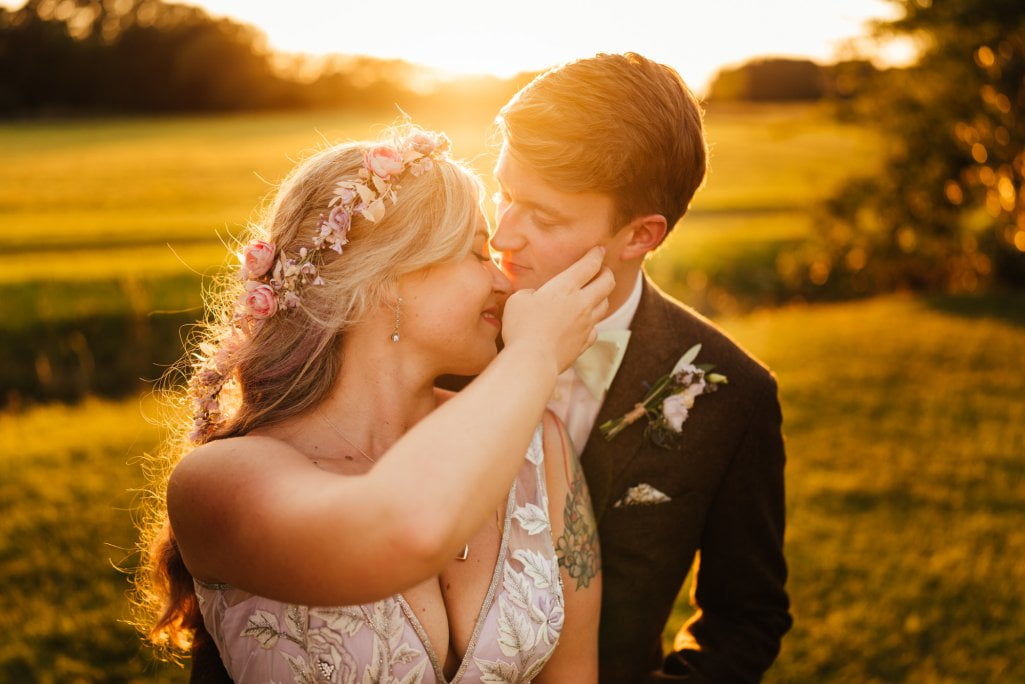 Couple embracing in sunset-lit field.